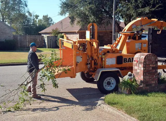 Wood chipper processing branches on a suburban street